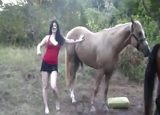 Dark-haired babe is jerking off and sucking giant horse shaft outdoors